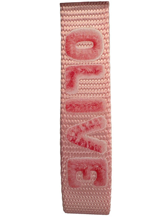 Pink woven belt with 'OLIVE' embossed on a light gray background