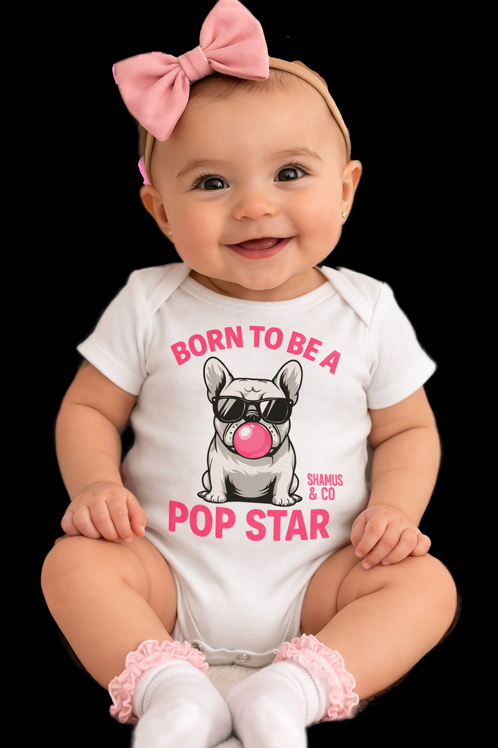 Baby wearing a Shamus & Co Born to be a POP STAR baby onesie with colorful star print and playful design.
