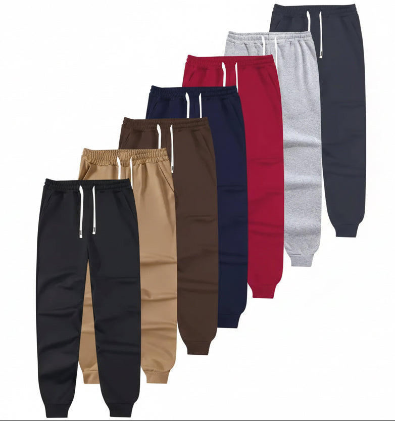 Set of six pairs of jogger pants in different colors on a white background.