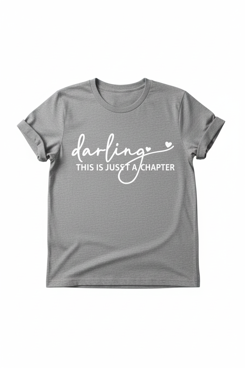 Grey adult graphic T-shirt by Shamus & Co with "Darling This Is Just a Chapter" motivational text printed on the front.