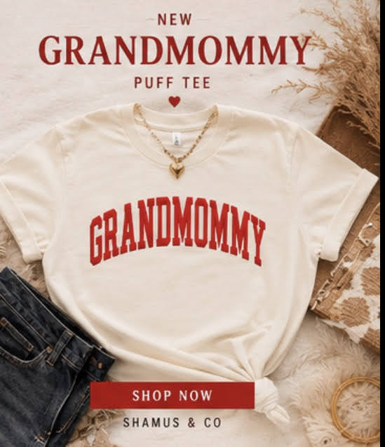 Beige t-shirt with 'NEW GRANDMOMMY' text, necklace, and denim jeans on a textured surface.