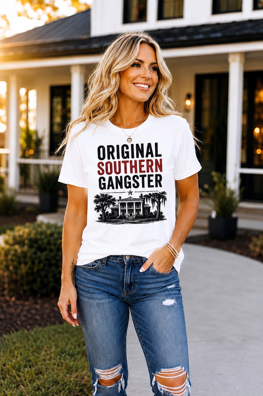Blonde woman wearing the Original Southern Gangster graphic t-shirt in white in front of a modern farmhouse.