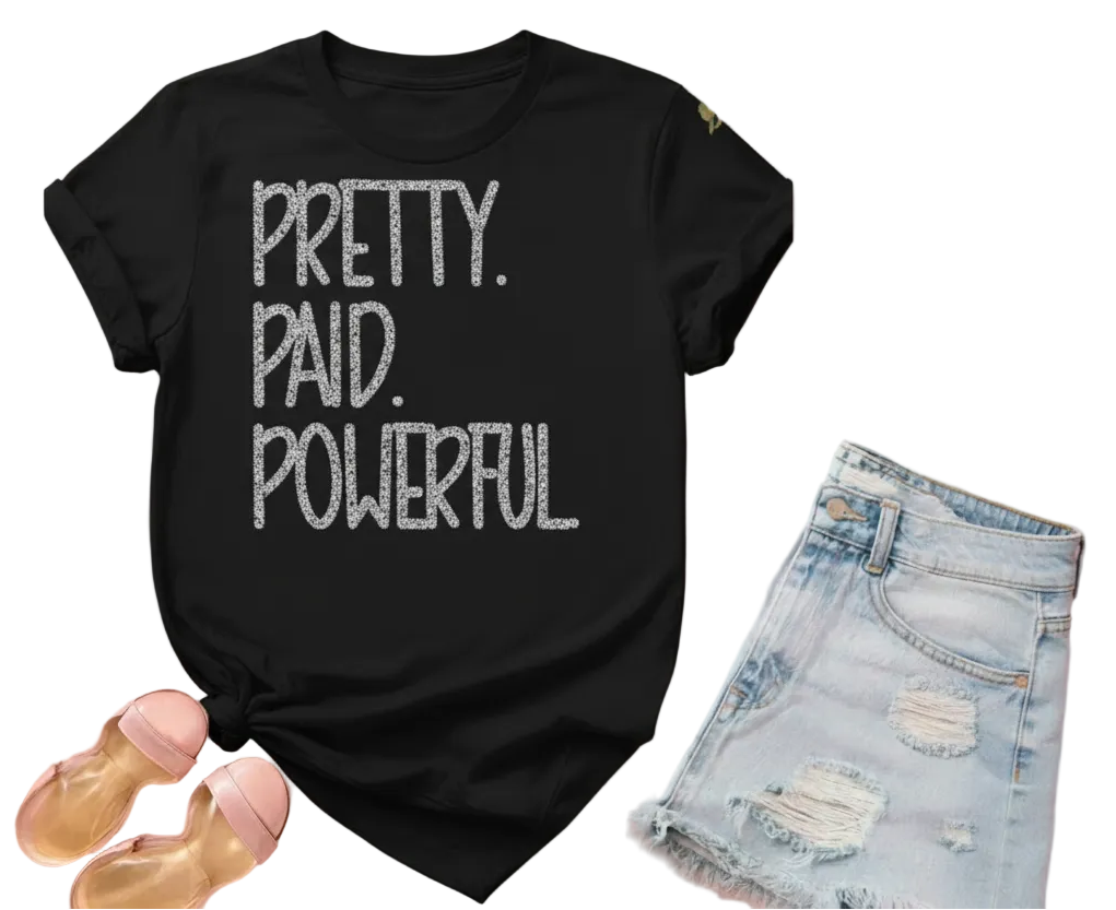 Black t-shirt with 'Pretty. Paid. Powerful.' text on a pink background with denim shorts and sandals.