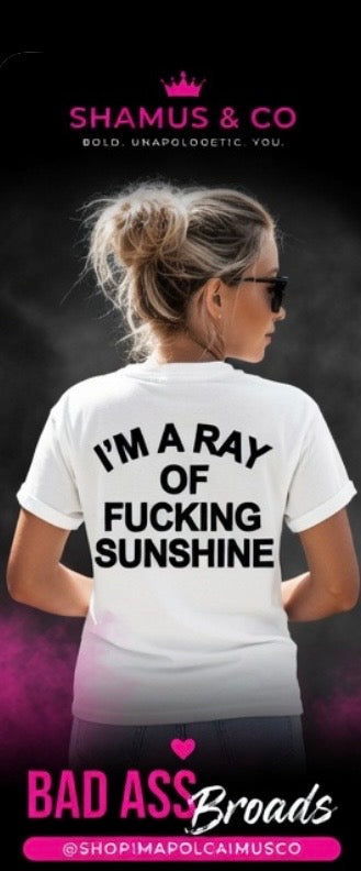 Person wearing a white t-shirt with text, I'I'm a ray of fucking sunshine', on a dark background with branding at the top and bottom.