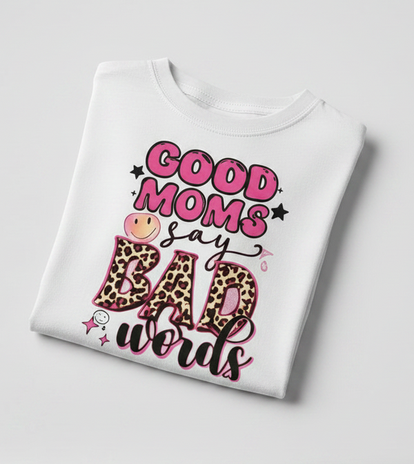 Adult Tee with 'Good moms say bad words' text, pink bow, and heart-shaped sunglasses on a light gray background