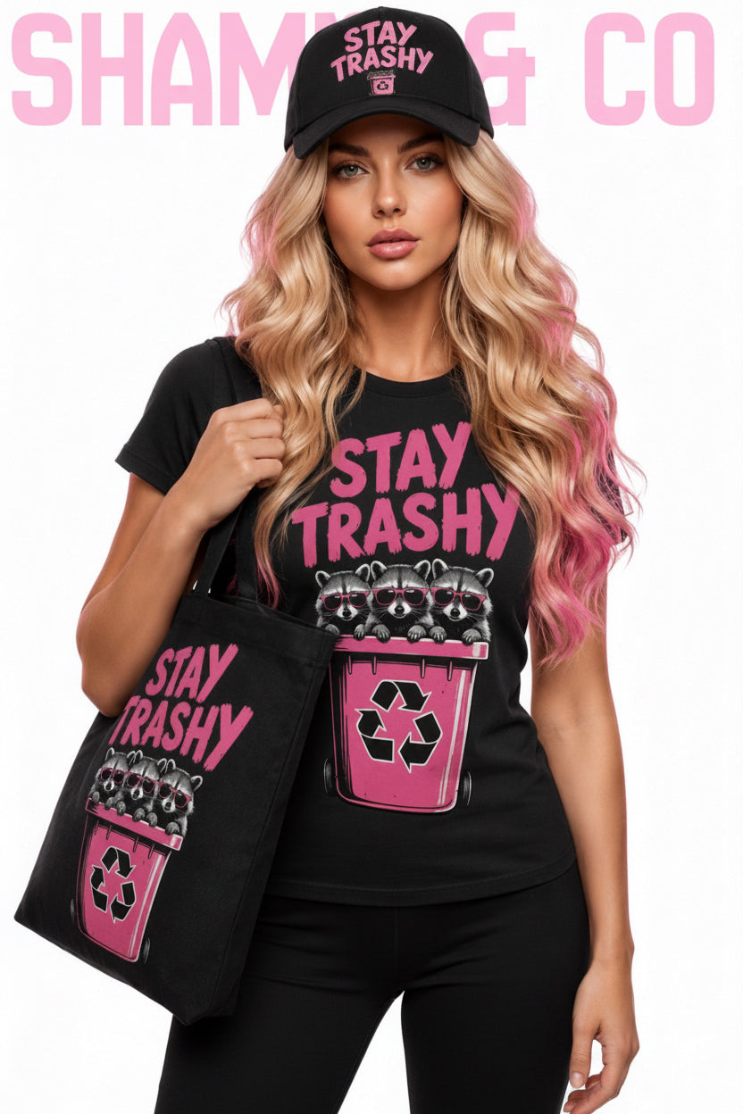 Woman wearing a black t-shirt and cap with 'Stay Trashy' text and graphic, holding a matching bag.