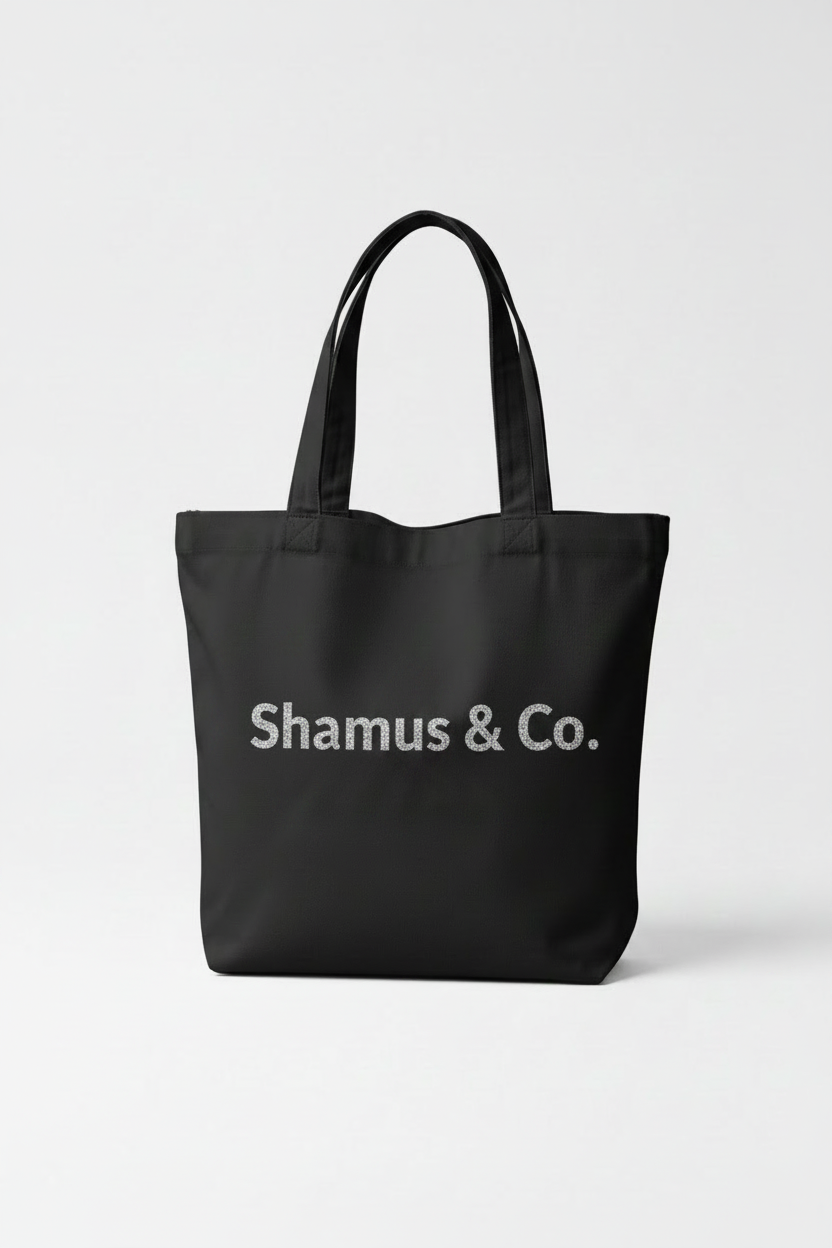 Personalized black canvas tote bag with a custom silver glitter HTV name, isolated on a clean white background with premium studio lighting.