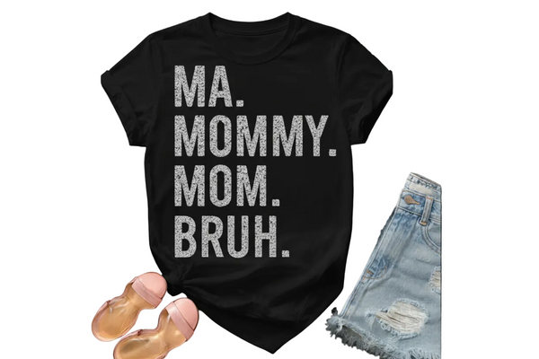 White t-shirt with 'MA. MOMMY. MOM. BRUH' text, paired with denim shorts and sandals on a black background.